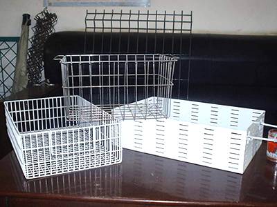Three galvanized wire baskets on a red table, and some wire panels beside table